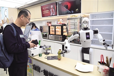 近日,在北京市海淀区中关村大街一座大厦内的便利店,机器人将抓取好的饮料交给顾客。 新华社记者 任超 摄